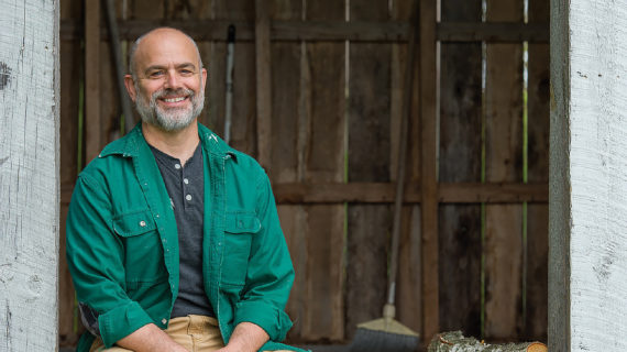 Michael Perry poses in a worn building on his farm.