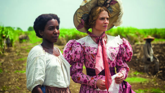 A black slave stands next to a white woman. Both look off screen into a field.