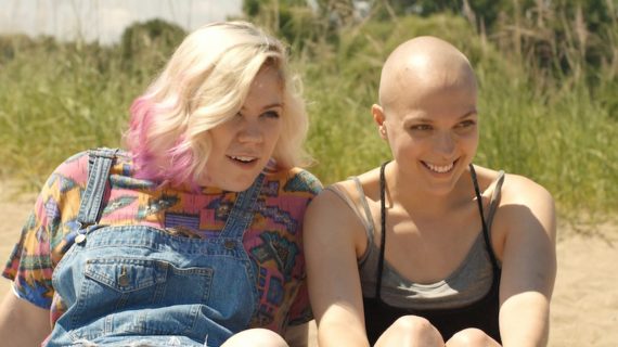 Two women smile while sitting next to each other