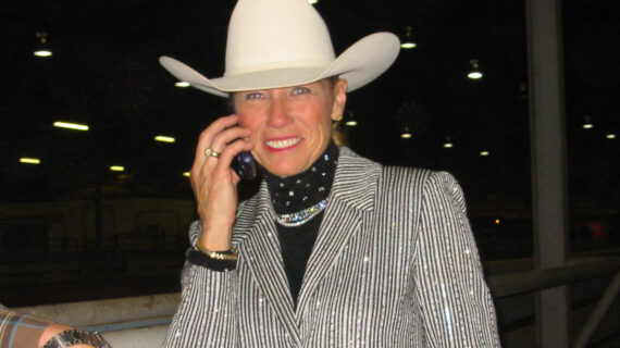 A woman wearing a cowboy hat smiles at the camera