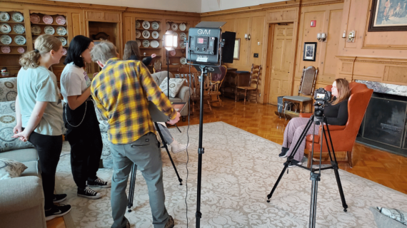 High school students use video camera equipment to conduct a documentary interview.