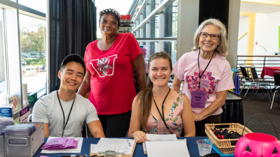 A group of volunteers smile behind a table