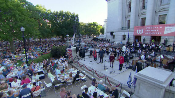 People listening to the Wisconsin Chamber Orchestra performing on the steps of the state capitol.