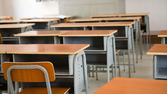 A close-up of a row of empty school desks.