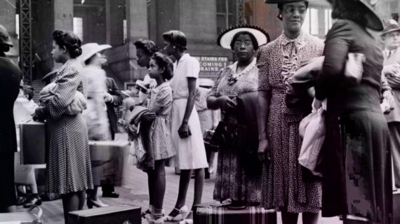 A group of Black Americans stand in line at a train station.