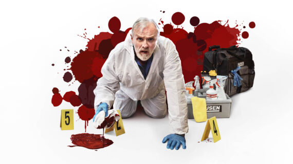 A middle-aged man with short gray hair and a beard is dressed in a white forensic-style cleanup suit and blue gloves, crouching on the floor while holding a bloodstained cloth.