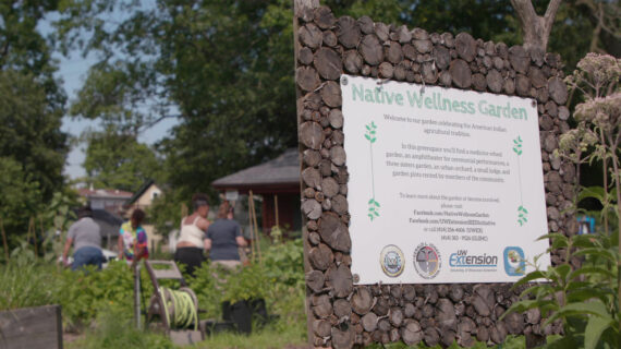 A “Native Wellness Garden” sign is displayed with a group of people gathered nearby, engaging with the natural environment.