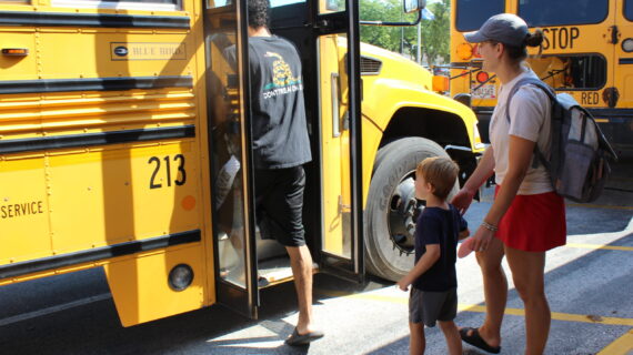 Caregivers and children board a school bus together.