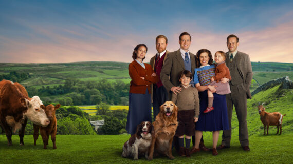 A group of individuals stands together against the backdrop of a rolling countryside.
