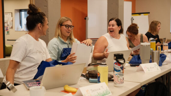 Educators at a professional learning event excitedly review educational materials together.