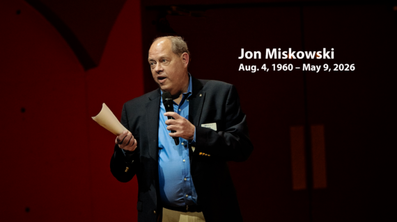Memorial graphic showing Jon Miskowski speaking into a microphone on stage, with text reading “Jon Miskowski, Aug. 4, 1960 – May 9, 2026.”
