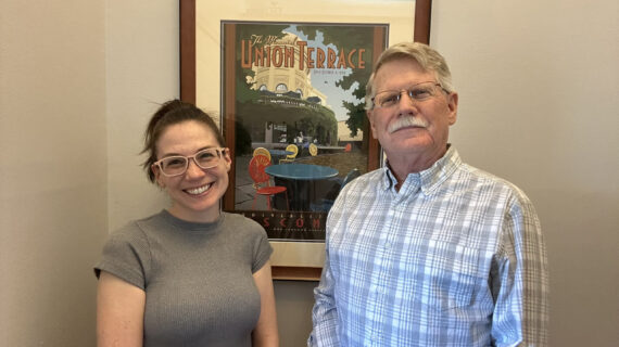 A woman and her father stand smiling at the camera.
