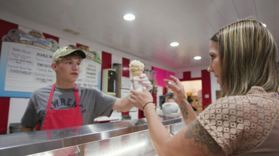 A woman receives an ice cream cone from a server behind the counter at the Windmill Ice Cream Shoppe in Tomahawk, Wisconsin.