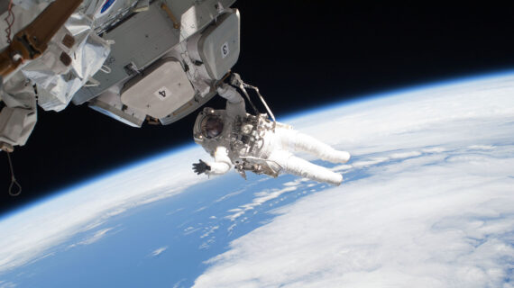 An astronaut floats in outer space with the Earth in the backdrop.